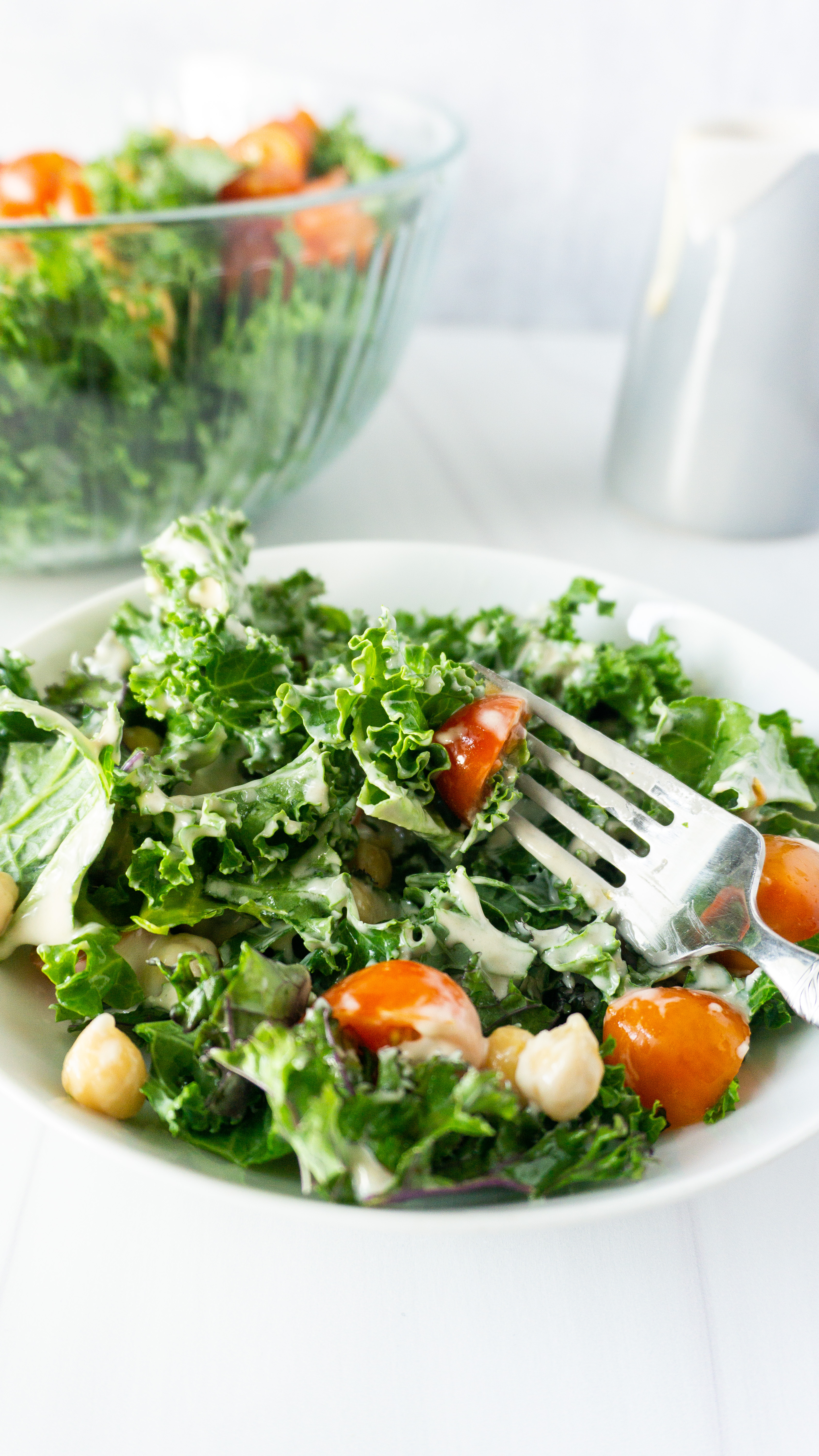 crunchy raw kale salad with a lemon tahini dressing on top with tomatoes and chickpeas as well.