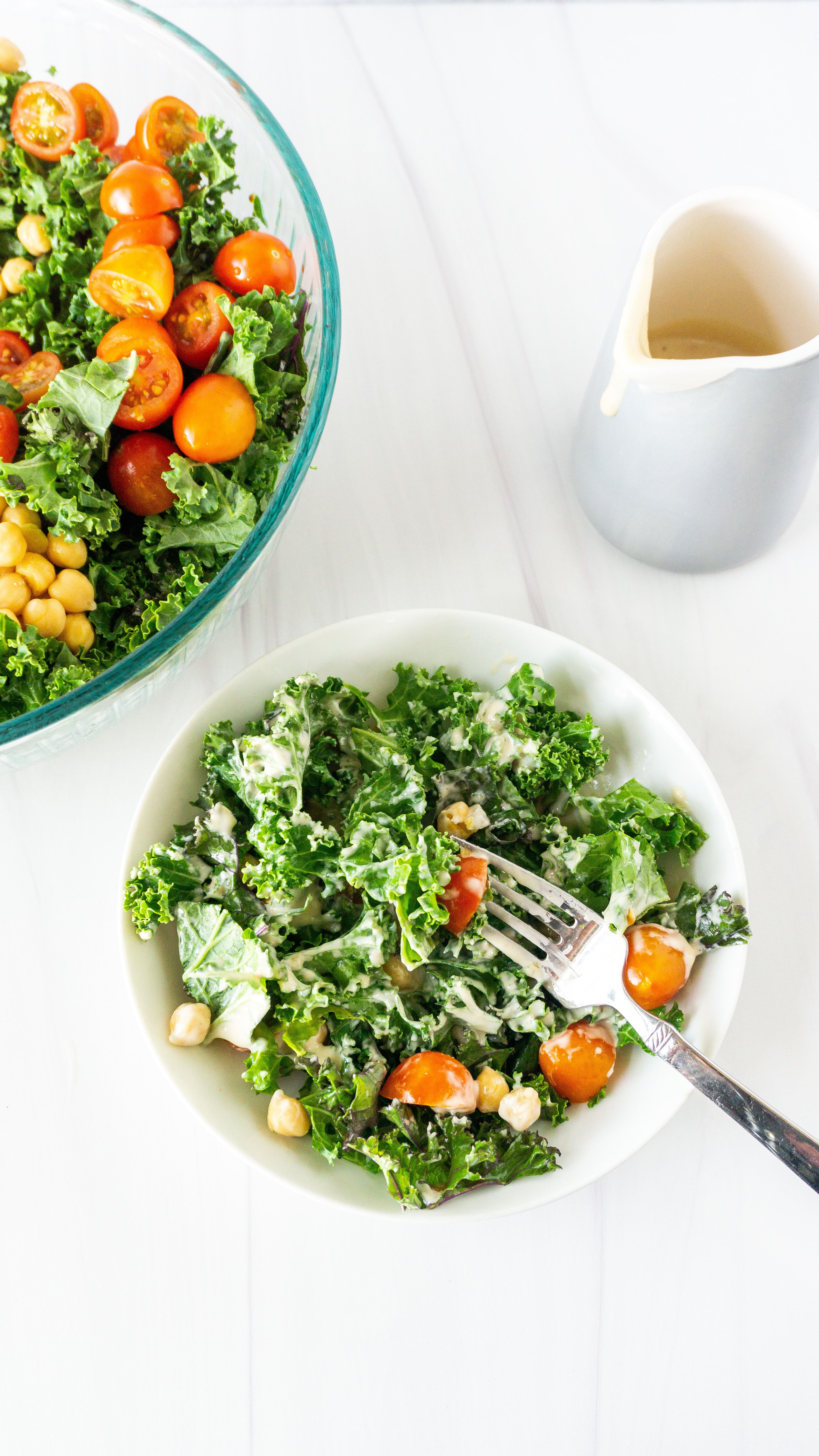 overhead photo of raw chickpea kale salad with lemon tahini dressing in a white salad bowl